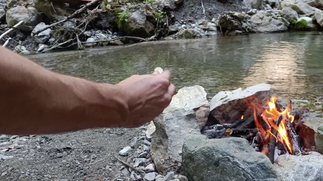 남자는 나무 막대기에 소시지를 놓고 모닥불에 요리