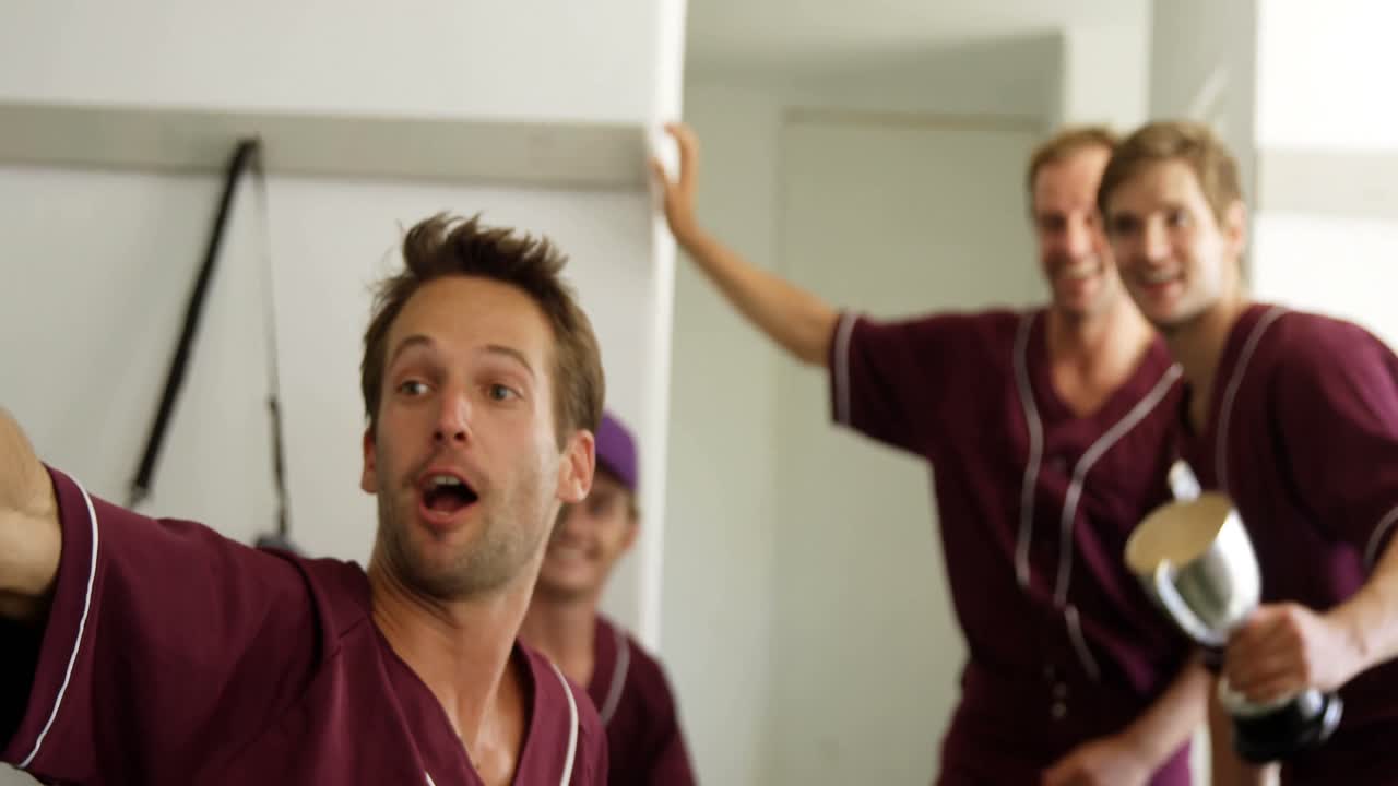 jugadores de béisbol tomando un selfie en el teléfono móvil en el vestuario