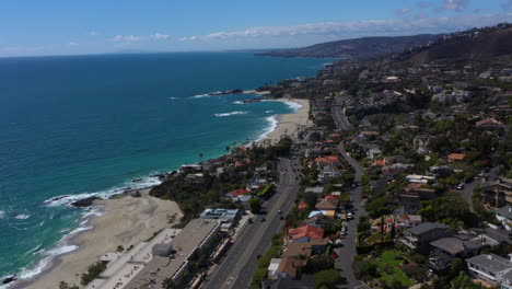 aerial drone footage traveling high above a coastal beach community along pacific coast highway route 1 in southern california on a bright sunny day