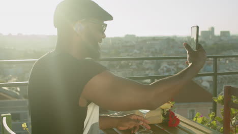 emocionado hombre gay negro mostrando flores a su amante a través de una videollamada