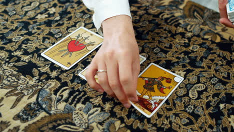 a woman giving a tarot reading with the tree of swords the two of pentacles and the fool cards