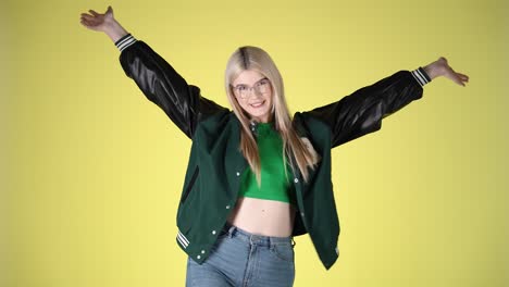 joyful young blonde woman dancing with arms raised, studio portrait