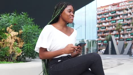 Self-assured-modern-black-woman-using-mobile-phone-in-city