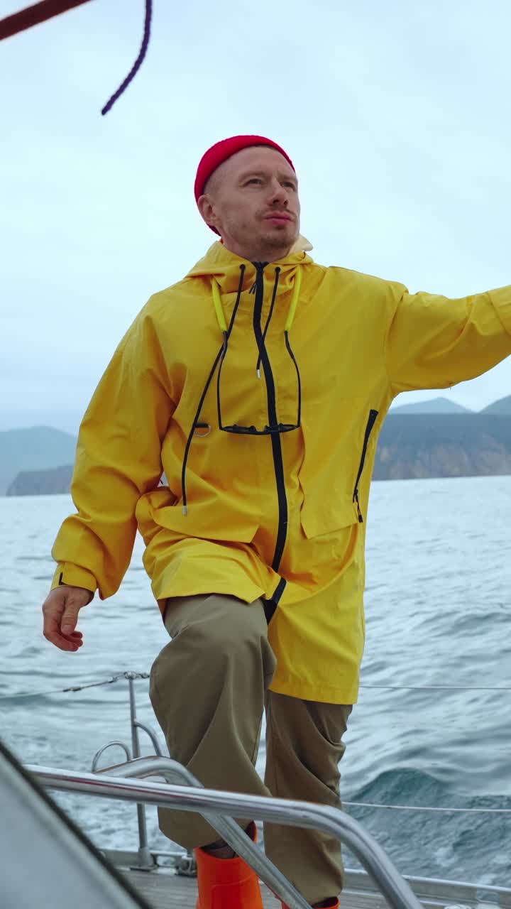 海上でヨットの上に立つ黄色のレインコートを着た男性