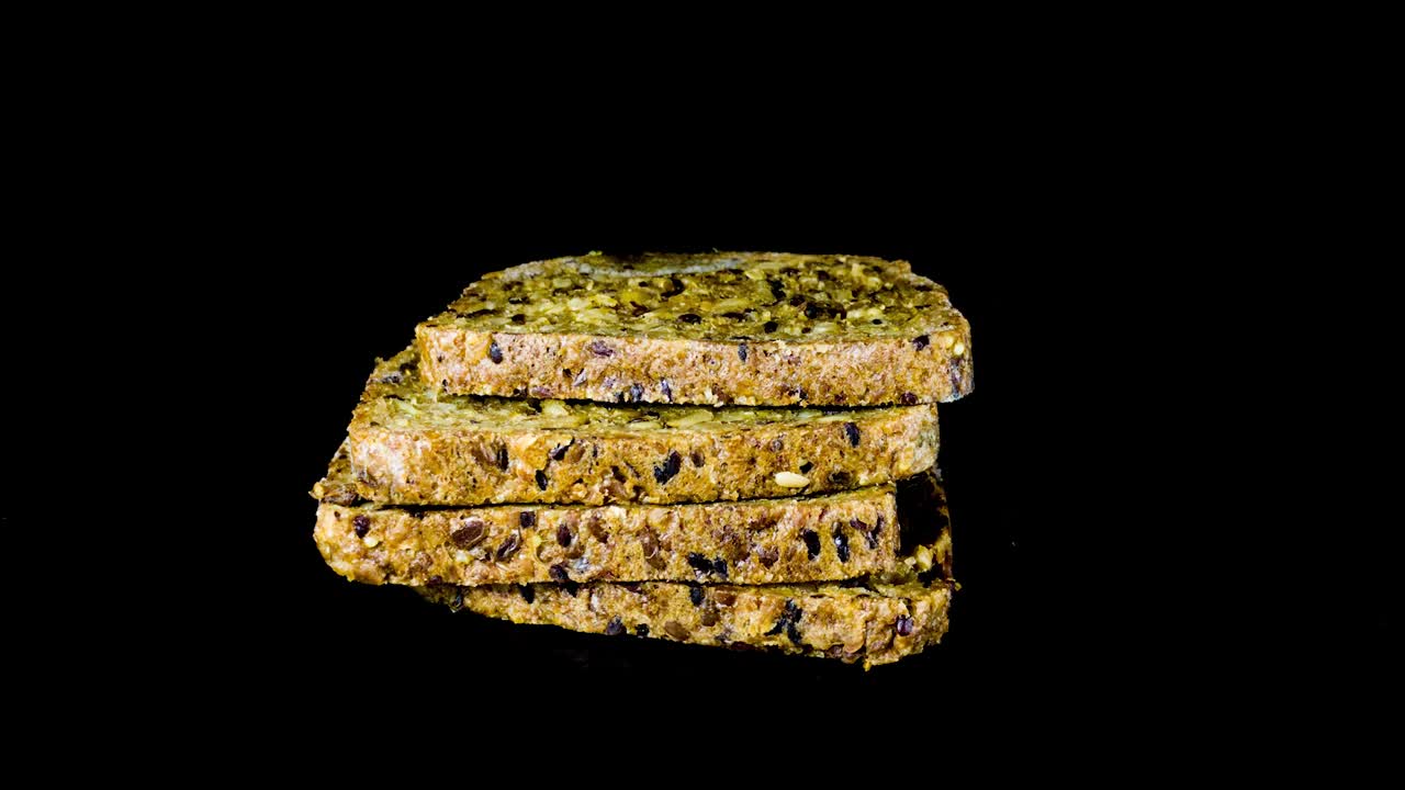 rebanadas de pan con semillas de sésamo estropeadas en el estudio, fondo negro - lapso de tiempo
