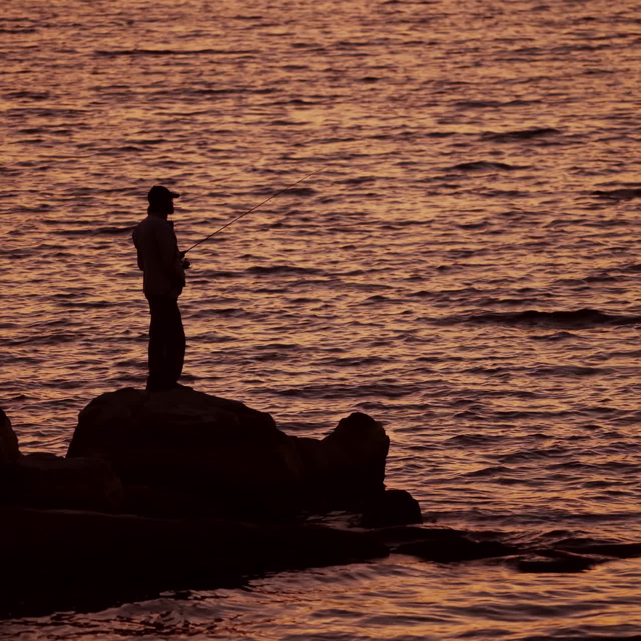 Fishermen on the rocks. Man's silhouette fishing at sunset. Freshwater fishing, catch of fish.