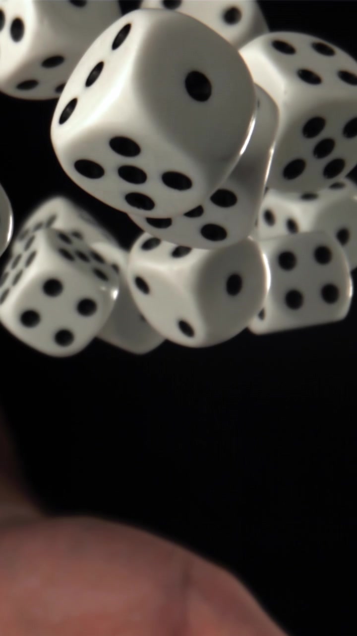 Hvide terninger kastet opad i slowmotion på sort baggrund