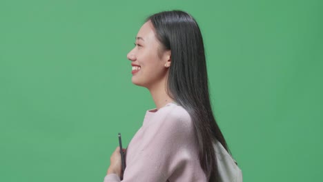 웃는 아시아 여성 학생이 태블릿을 들고 녹색 스크린 스튜디오에서 는 측면 시각