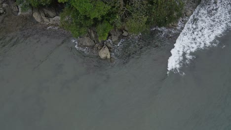 Waves-gently-crashing-onto-the-rocky-shoreline-of-Playa-La-Vaca-Beach-near-Quepos,-Costa-Rica