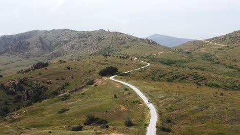 White-car-drives-on-a-light-road-among-the-green-nature-of-North-Macedonia-on-a-sunny-day