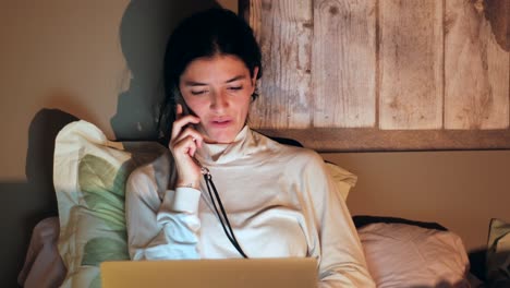 young happy caucasian woman talking on phone and using laptop sitting at home