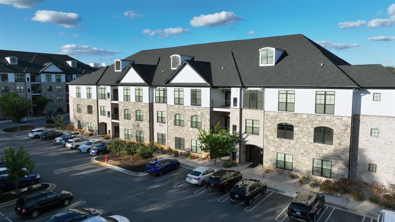 Modern residential apartments with parking cars during sunny day and blue sky. Aerial view. New developed housing area in suburb of town