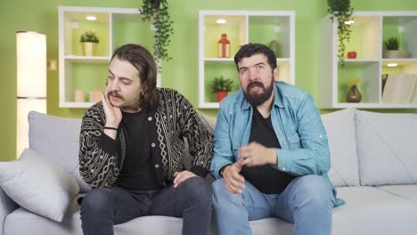 two depressed and worried friends sitting on sofa at home.