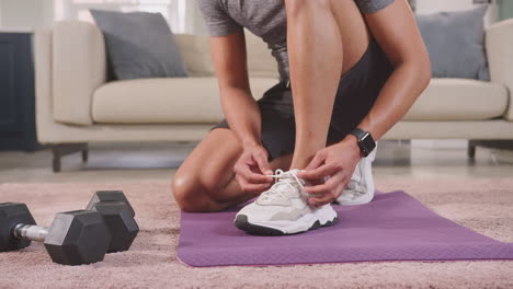 Close-up-of-man-in-fitness-clothing-at-home-fastening-trainers-before-exercising---shot-in-slow-motion