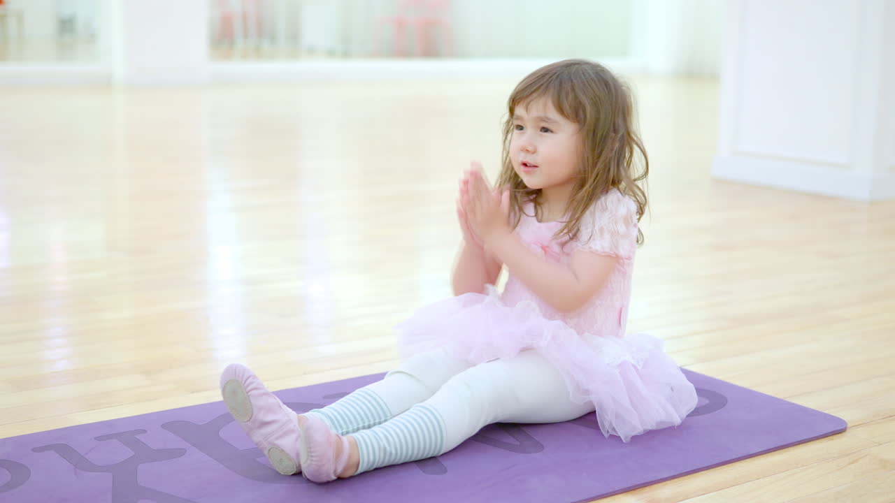 niña pequeña en leotard o vestido tutu practicando estiramiento en el estudio de clase de ballet