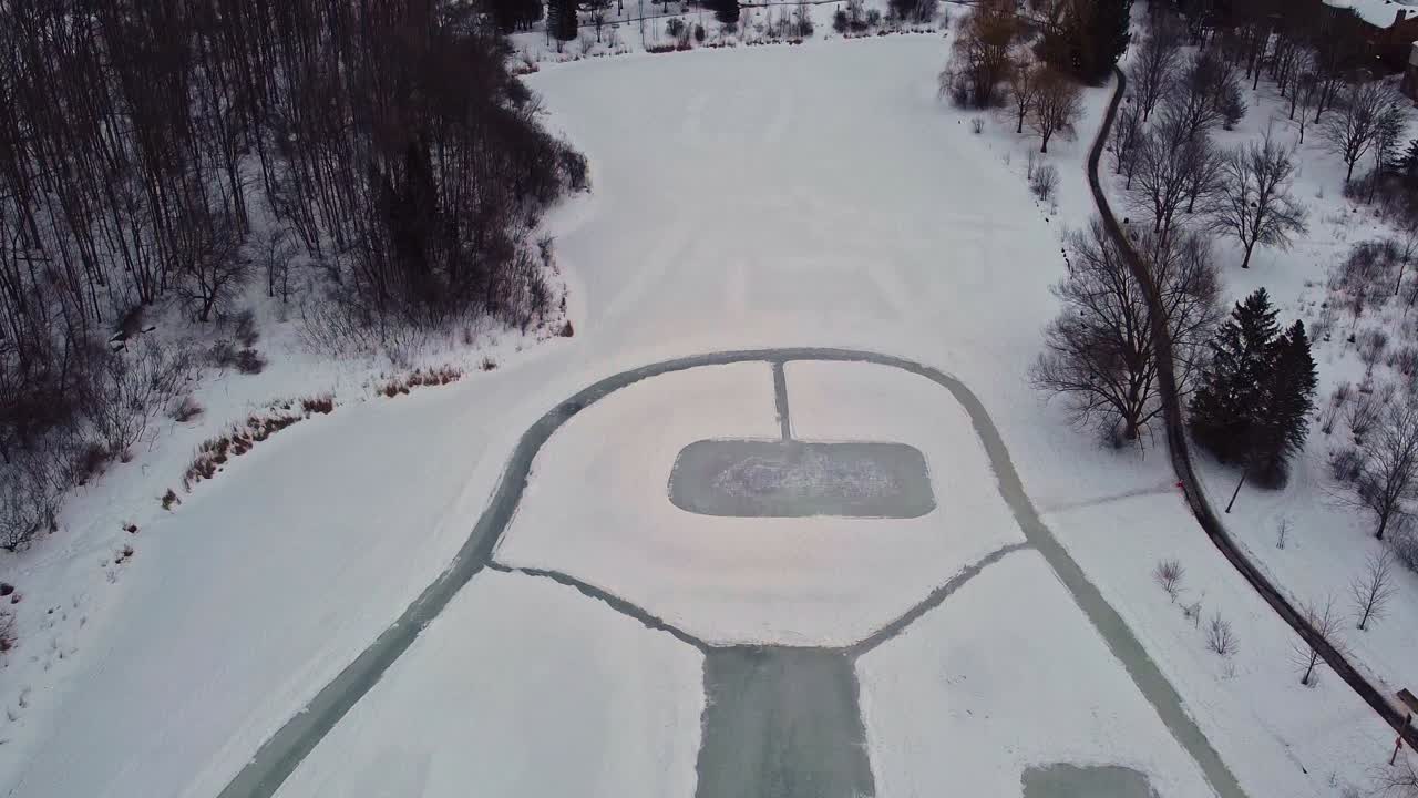 Overhead drone shot of several outdoor rinks on a pond in Canada