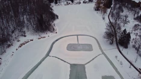 overhead drone shot of several outdoor rinks on a pond in canada