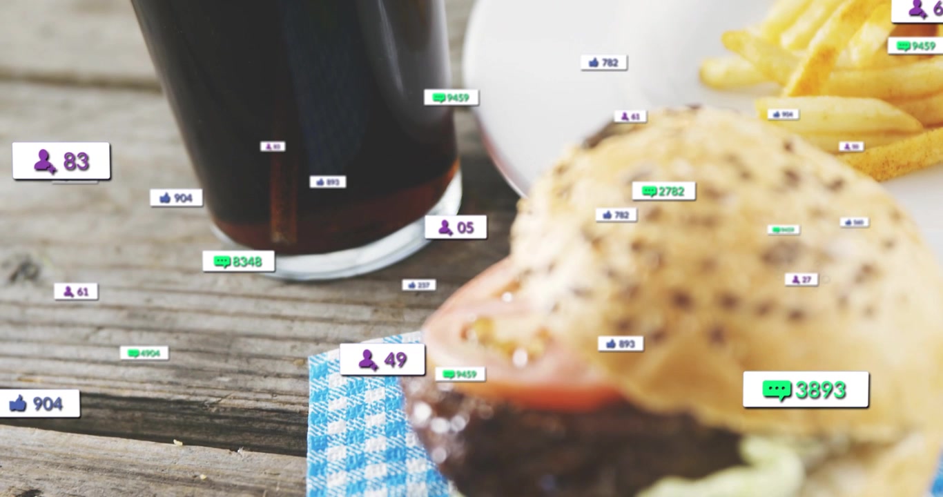 Animated badges spawning around glass, drifting to burger, showing social engagement on tabletop