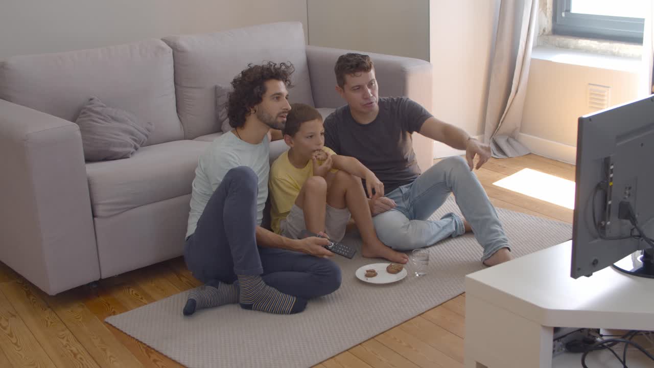 niño concentrado y sus padres comiendo galletas y viendo películas