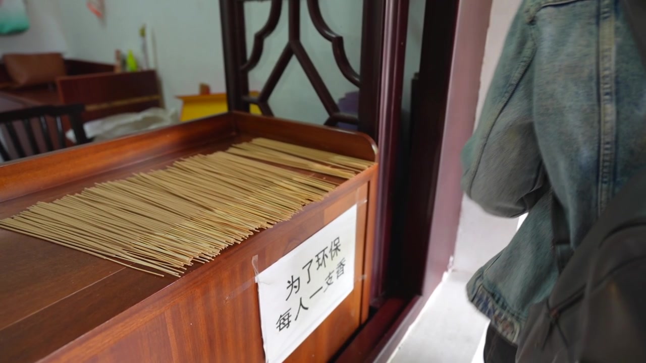 Close up of a hand picking up an incense stick from a wooden dispenser in a Chinese temple