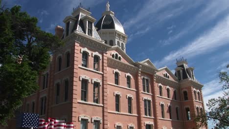 Tilt-Up-To-An-Old-Victorian-Building-With-An-American-Flag-In-Front