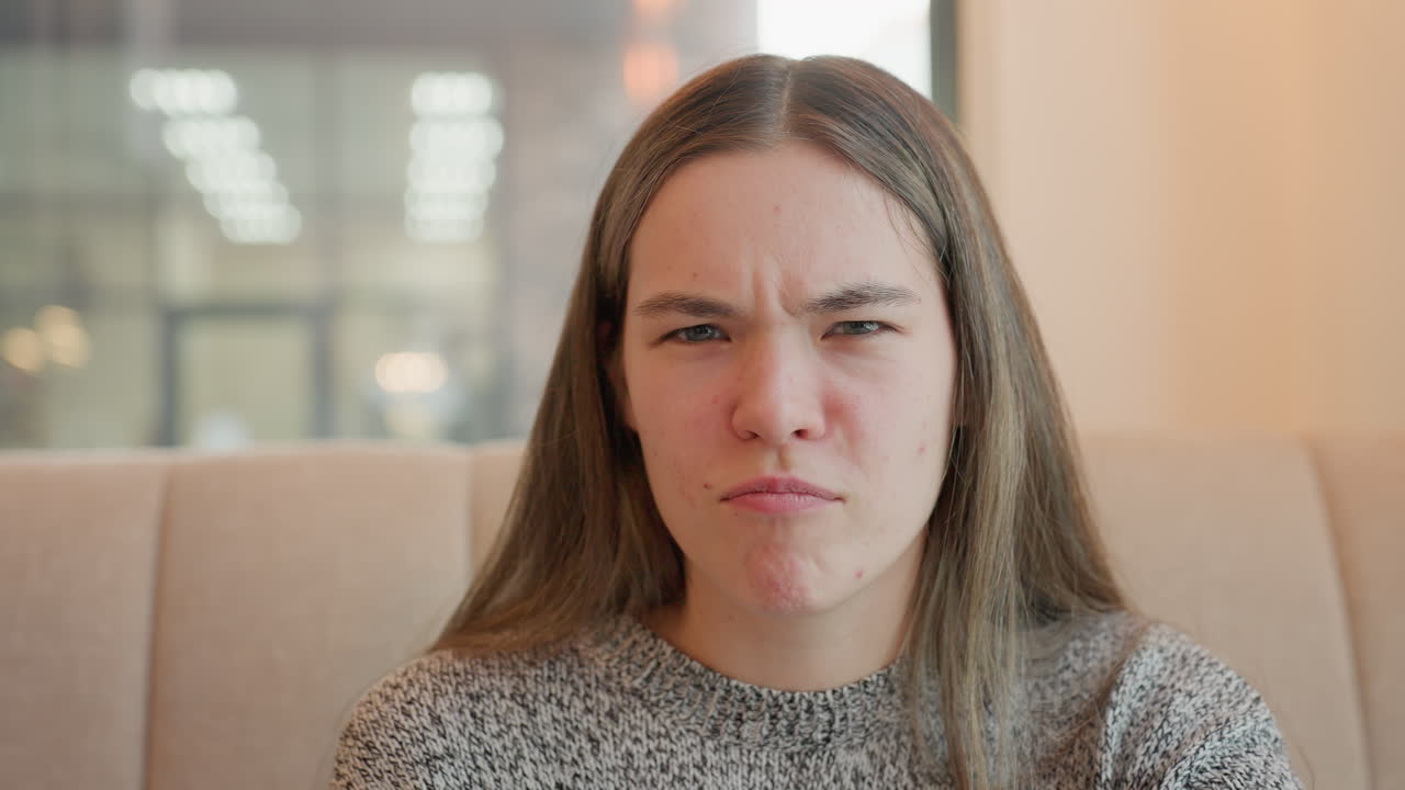 Cheerful young girl with playful expressions, seated at buffet table, making fun gestures and smiling joyfully, creating a lively atmosphere with casual, friendly vibes in a cozy indoor setting