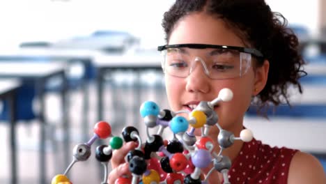 Attentive-schoolgirl-experimenting-molecule-model-in-laboratory