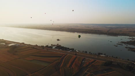 stunning 4k aerial footage of a drone filming hot air balloons. flying over farming fields and river. filmed on a beautiful summer morning. part of a hot air ballon festival in prelog, croatia.
