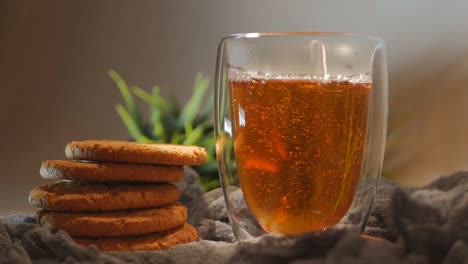 vertiendo té caliente en un vaso de vidrio doble. el té caliente se vierte en un vidrio de paredes dobles. el té en un cristal transparente y las galletas están girando. video de bucle. primer plano. rotación