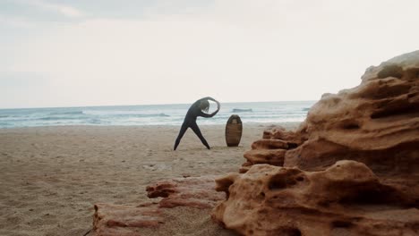 surfista estirándose en la playa al amanecer