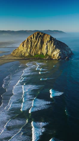 Splendid scenery of Pacific Ocean coastline with huge rock on the beach. White foamy tides coming to the shore. Vertical video
