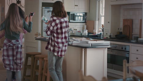 happy teenage girls dancing in kitchen eating pizza having fun celebrating together enjoying hanging out together on weekend