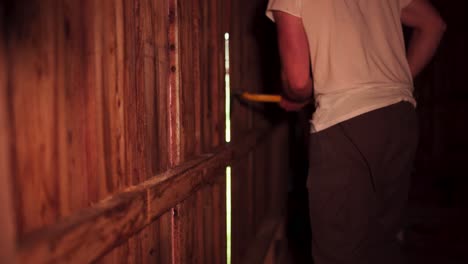 vista recortada de un hombre desmantelando las paredes de tabla de madera de una casa de granero usando una palanca