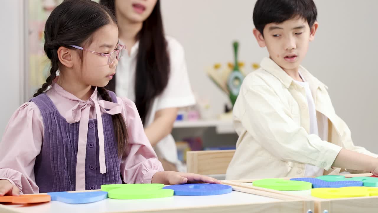 明るい教室で、幼い生徒たちが木のブロックを使って、微細運動能力と色の認識を練習しています。