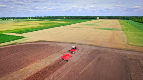 Agricultural-tractor-with-trailer-plowing-ploughing-field.-Rural-farming