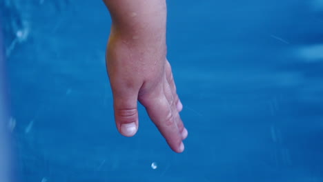 toma en cámara lenta de la mano del niño tocando el agua en movimiento mientras un pequeño barco de pesca viaja en el océano atlántico en portugal