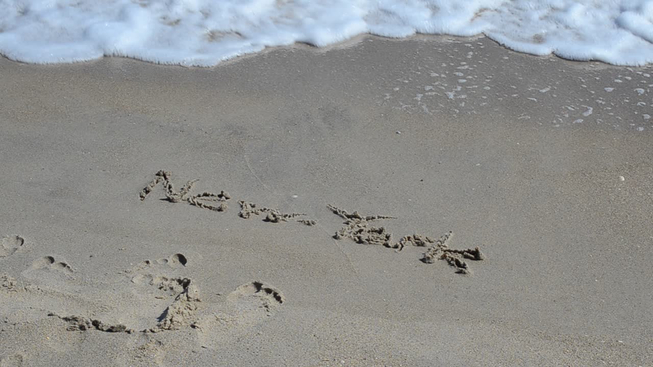 Iscrizione New York su una spiaggia. L'iscrizione New York su una spiaggia viene spazzata via da un'onda