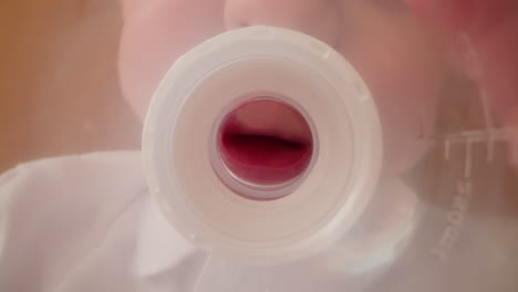 child takes plastic bottle with nipple standing in kitchen