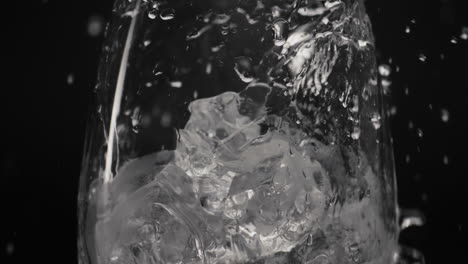 splashed water pouring ice glass closeup slow motion. organic cocktail concept