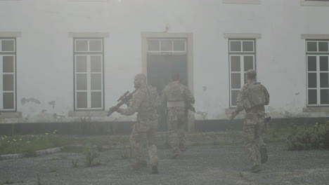 back view of soldiers with rifles storming building