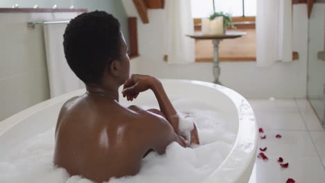 back view of african american attractive woman relaxing in foam bath in bathroom