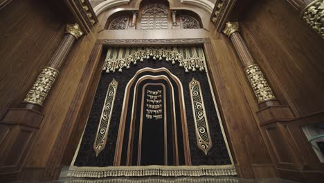 ornate aron kodesh (torah ark) in synagogue with detailed carvings and hebrew inscriptions