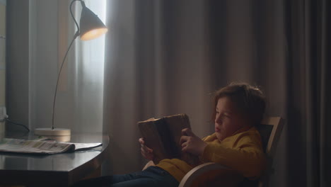 Young-boy-reading-old-book-at-table