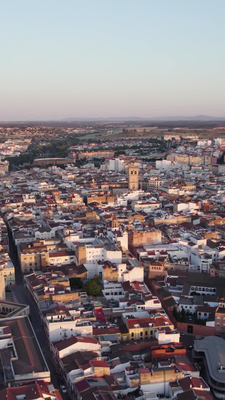 Ripresa aerea verticale orbitante che cattura il paesaggio urbano di Badajoz durante il tramonto, con una luce calda che illumina il paesaggio urbano