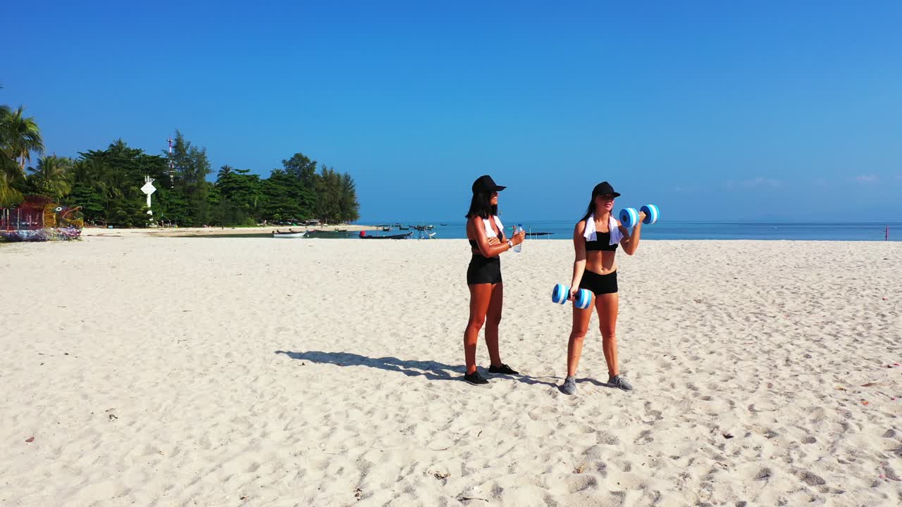 Colorful landscape on paradise beach with white sand near blue sea where beautiful girls exercising gymnastics on fresh air of morning in Malaysia