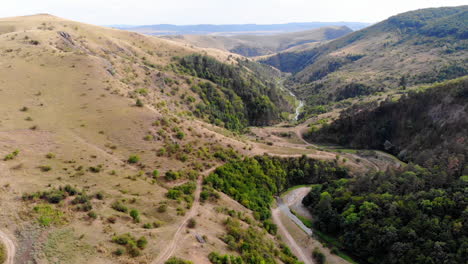 drone flying over a small canyon separating forest and grass land