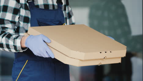 a courier holds the pizza box in protective gloves to deliver it safely 1