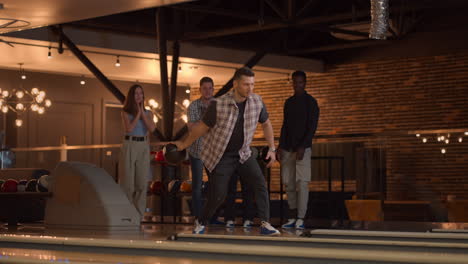 a young man throws a bowling ball and knocks out a shot with one throw and hugs and rejoices with his friends. multi-ethnic group of friends bowling