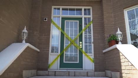 crime scene do not cross yellow tape across front door of brick home entranceway