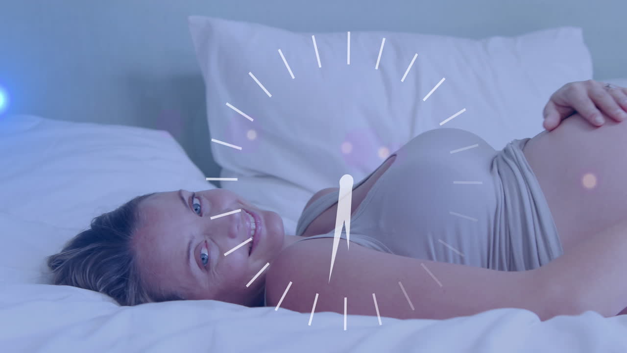 침대에 누워서 배를 문지르는 행복한 임신한 백인 여성